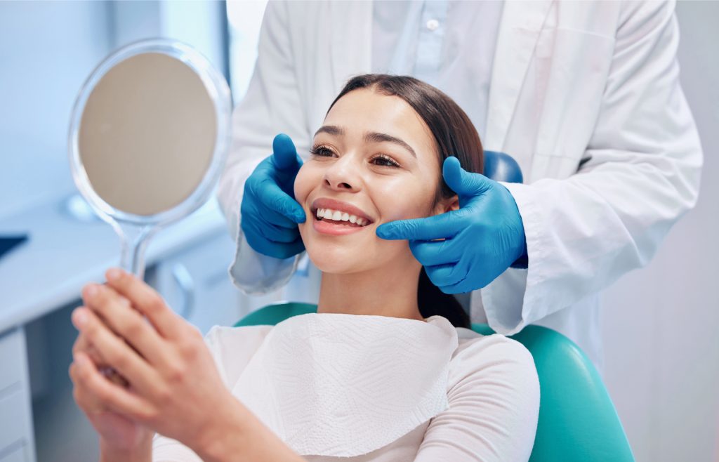 Woman Looking At Her Teeth In A Mirror At A Dentist's Office