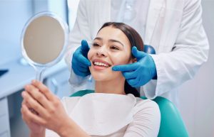 Woman Looking At Her Teeth In A Mirror At A Dentist's Office
