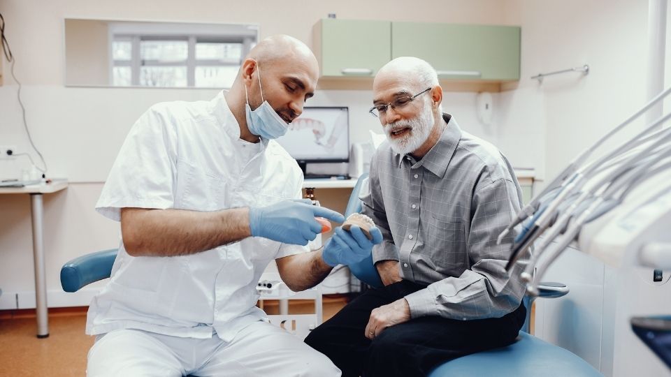 Dentist Showing Artificial Teeth to Senior Patient