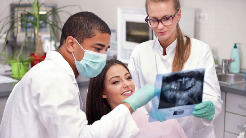 Dentist & Assistant With Dental X-ray, Showing to Patient