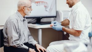 Senior Man Consulting Dentist About Dental Implants